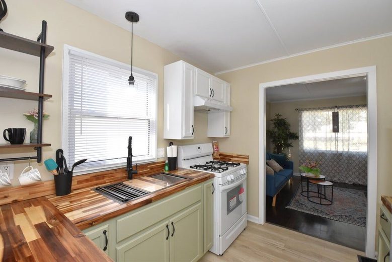 After photo of a renovated kitchen with butcher block counter tops and light green cabinets