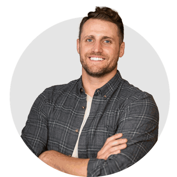 A man in a plaid shirt is smiling with his arms crossed.