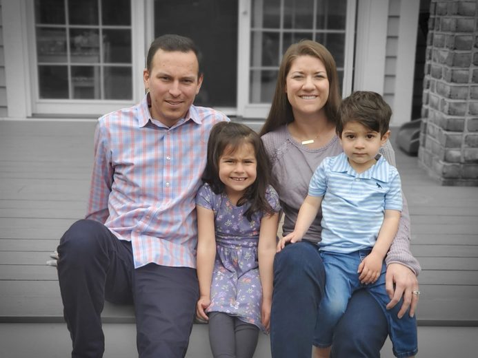 A family is sitting on a porch posing for a picture.
