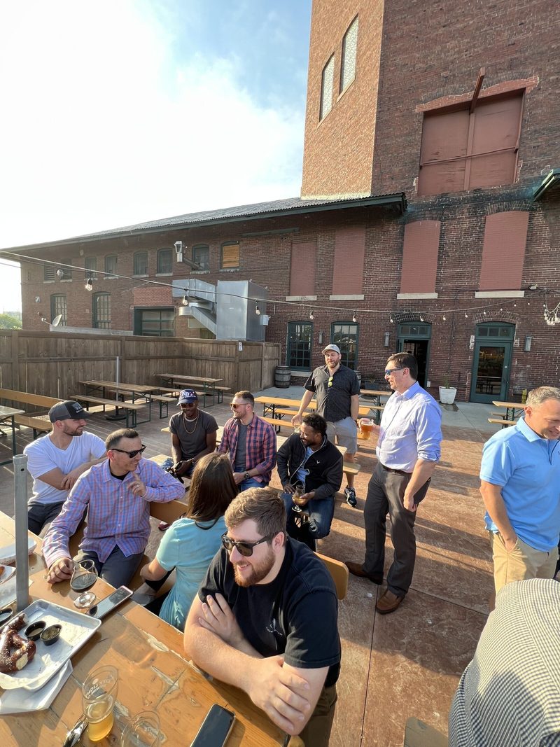 A group of men are sitting at a table in front of a brick building