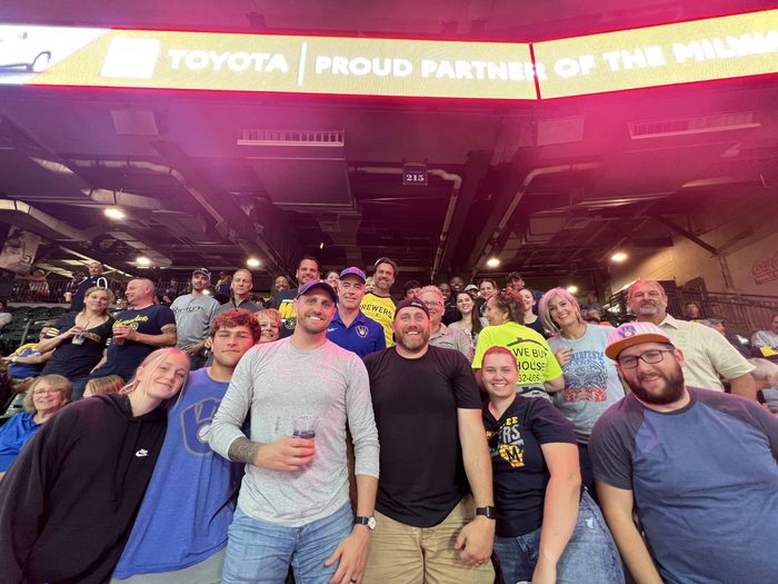 A group of people are posing for a picture in front of a toyota sign.