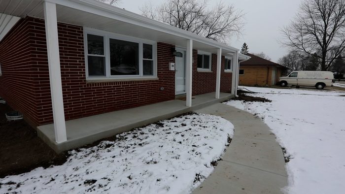 A brick house with a porch and snow on the ground