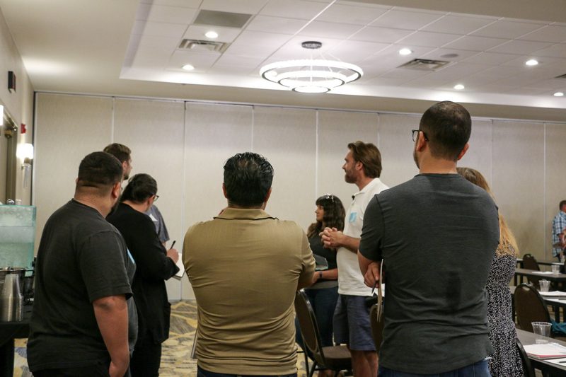 A group of people are standing in a room talking to each other.