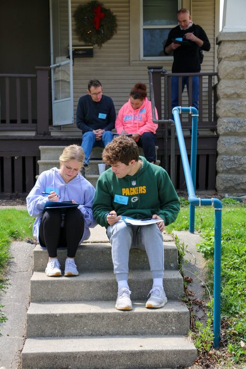 A group of people are sitting on the steps of a house.
