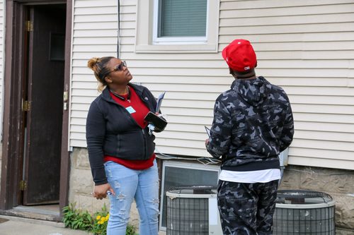 A woman is talking to a man in front of a house.