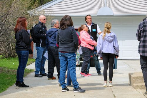 A group of people are standing outside of a house.