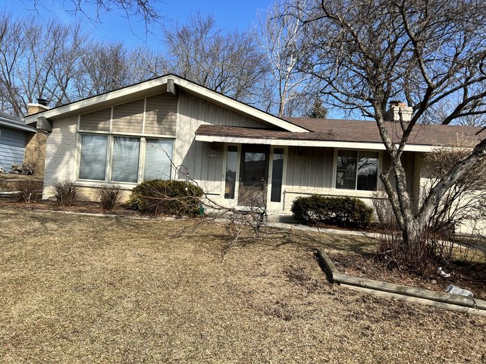 A house with a lot of windows and a lot of leaves on the ground.