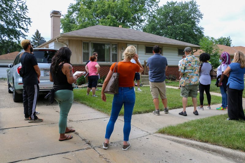 A group of people are standing in front of a house.