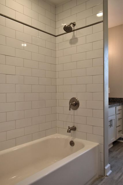 A bathtub in a bathroom next to a shower with white tiles.