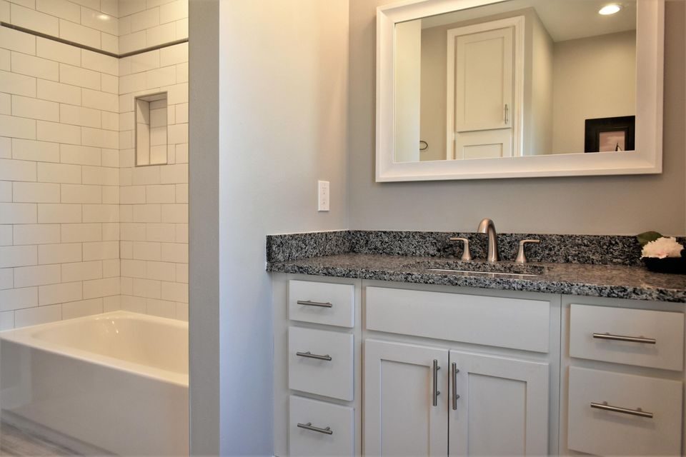 A bathroom with a sink , mirror and bathtub.