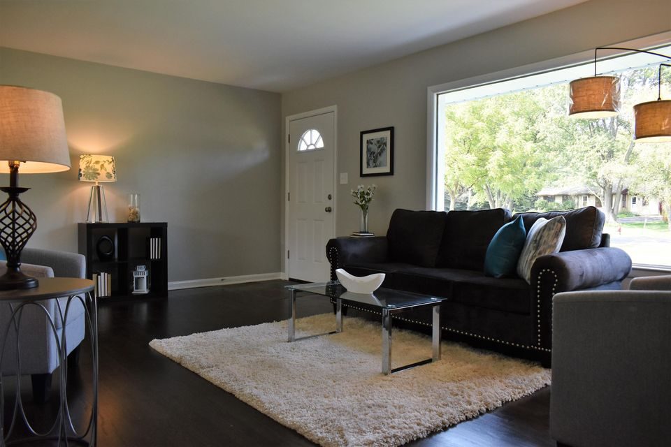 A living room with a black couch and a white rug