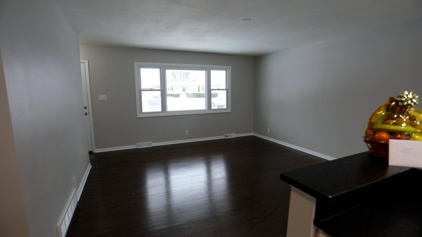 An empty living room with a bowl of fruit on the counter