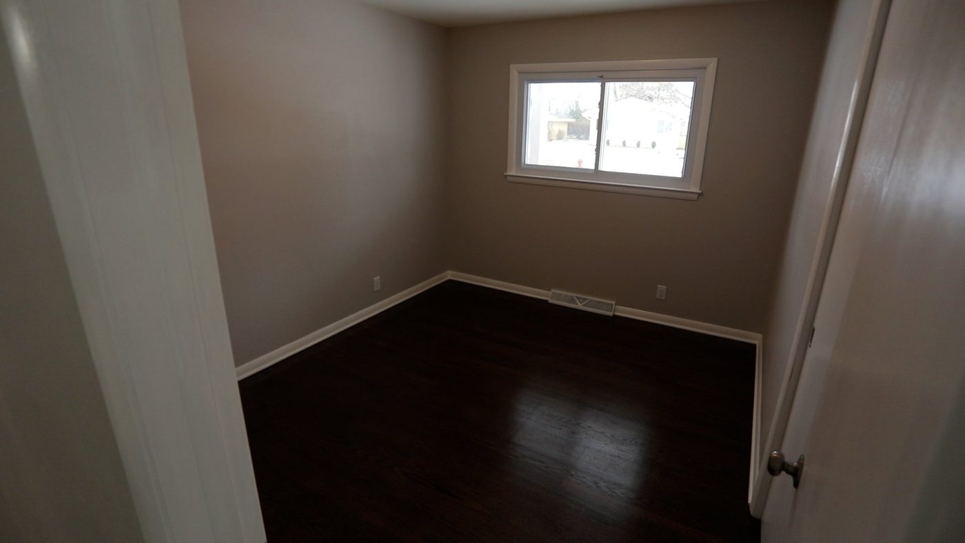 An empty room with hardwood floors and a window