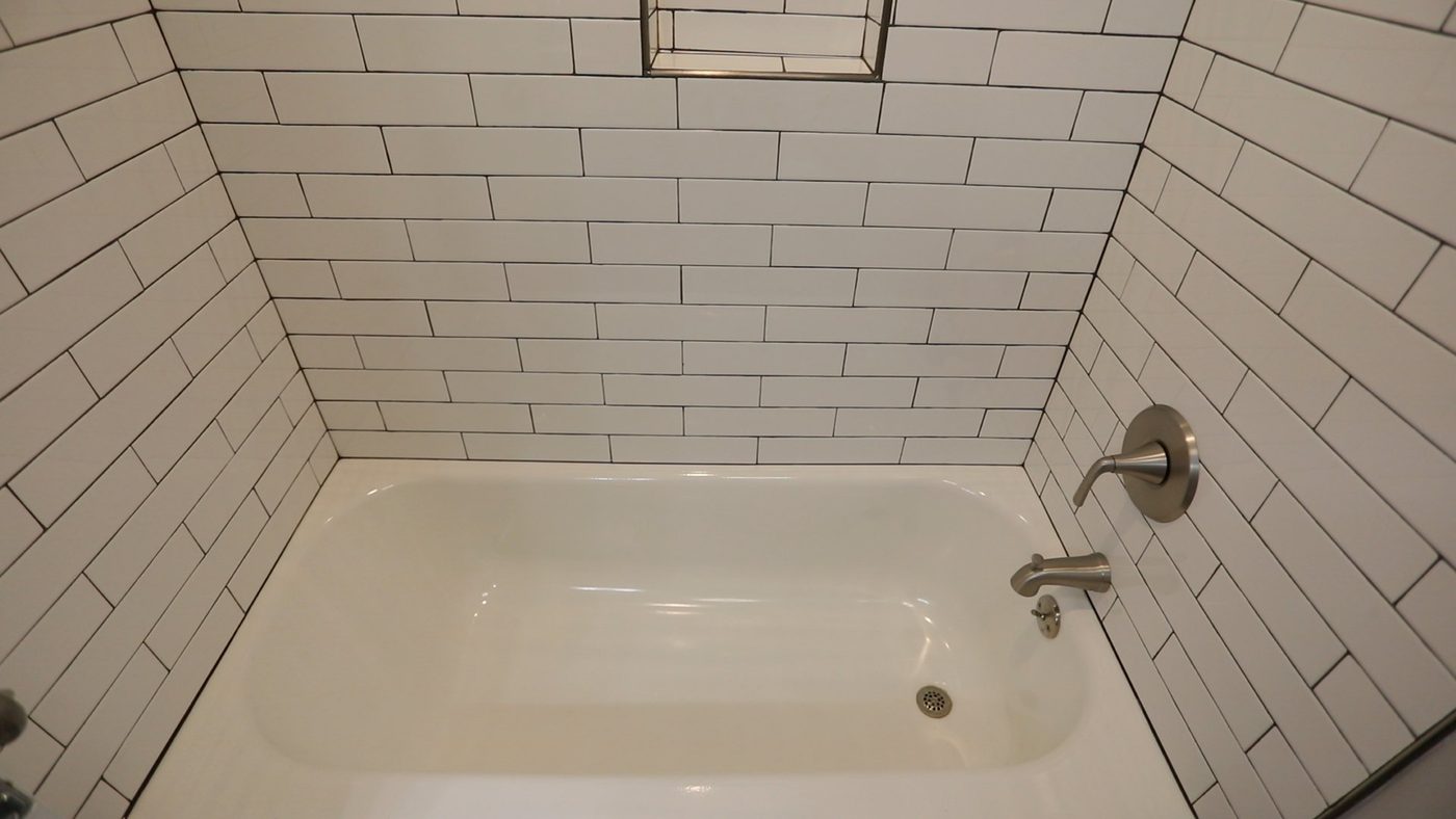 A bathtub in a bathroom with white brick walls