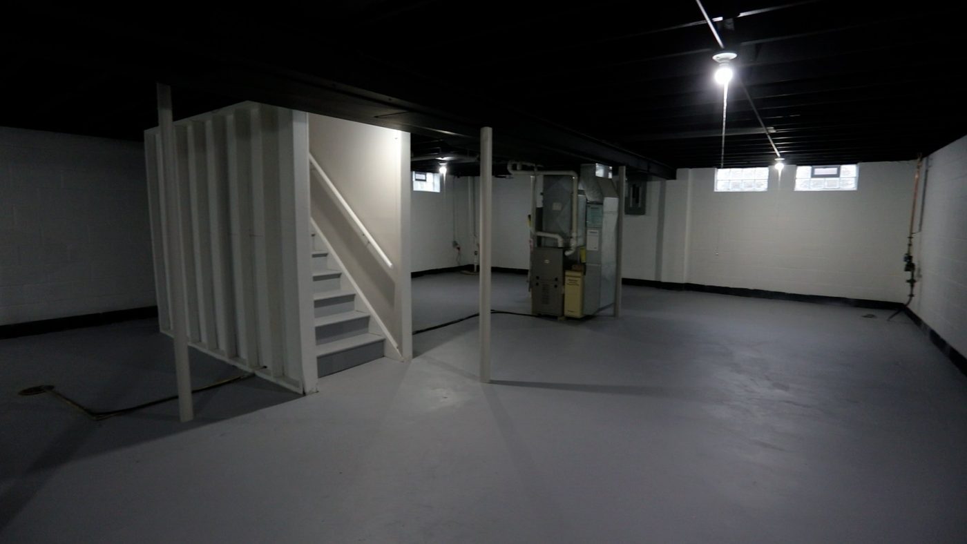 An empty basement with stairs leading up to the second floor.