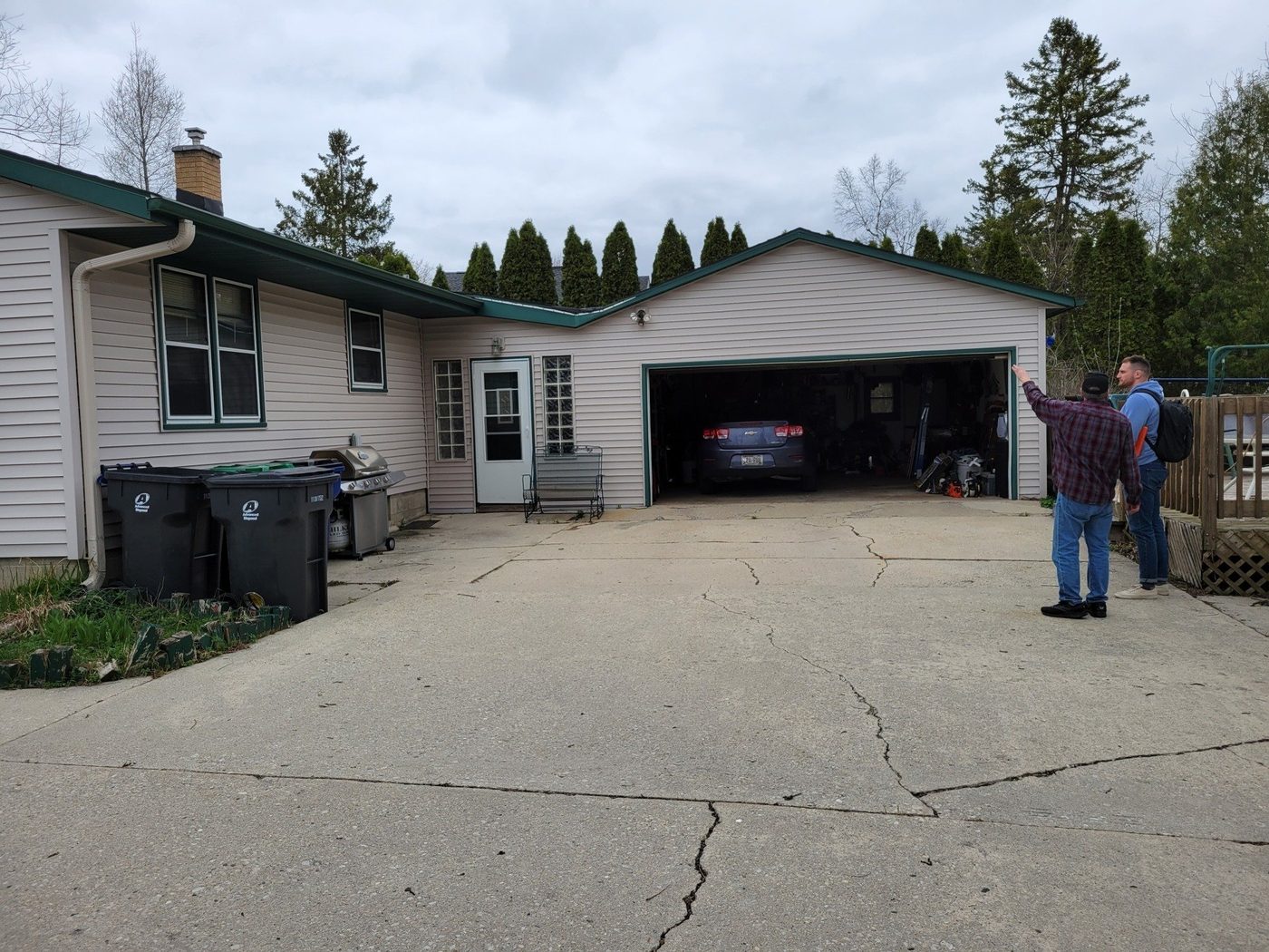 A man stands in front of a house with a car in the garage